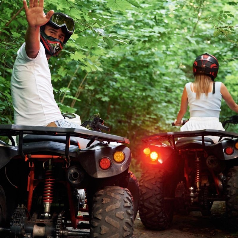 Dans la forêt, un homme et une femme sont sur un quad à l'extérieur